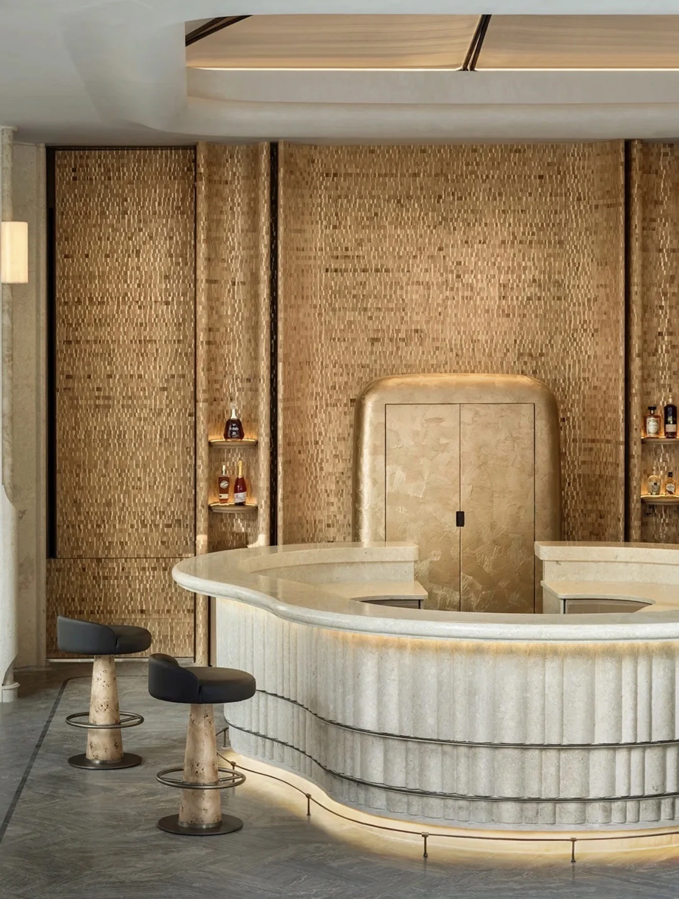 Hospitality interior with warm textured wall surfaces behind a curved pale counter and dark stools